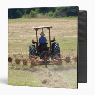 A young boy driving a tractor harvesting binder