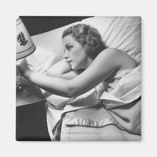 Aimant Jeune femme allongée sur le lit éteint la lampe