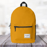 American Nostalgia Classic Simple Minimal Mustard Printed Backpack<br><div class="desc">This american nostalgia style classic backpack in mustard yellow features a patch style emblem with a monogram name and framed border,  featuring informal handwritten script and modern block typography. The text can be customized with your name for a design as unique as you are!</div>