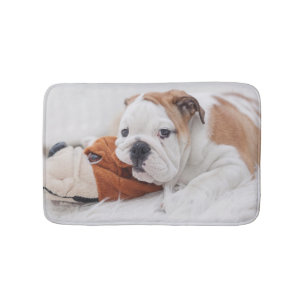 An English Bulldog Puppy Playing With A Bulldog Bath Mat