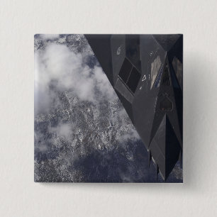 An F-117A Nighthawk flies high over the mountai 2 Inch Square Button