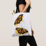 Artistic Watercolor Monarch Butterfly Nature Art Tote Bag<br><div class="desc">The design features two vibrant monarch butterflies in mid-flight, rendered with artistic paint splatters in warm shades of orange and yellow. This nature-inspired graphic captures the delicate elegance of spring wildlife. It makes a wonderful gift for gardeners, entomology enthusiasts, nature lovers, or anyone who appreciates the symbolism of freedom and...</div>