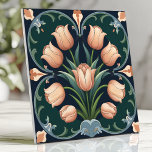 Arts and Crafts Tulip Bouquet on Deep Green Tile<br><div class="desc">Bring vintage charm to your space with this Arts and Crafts-inspired tile featuring a tulip bouquet in soft peach tones against a deep green background. Delicate scrolling details and a symmetrical design evoke timeless elegance, making it perfect for backsplashes, accent walls, or adding a touch of classic beauty to your...</div>