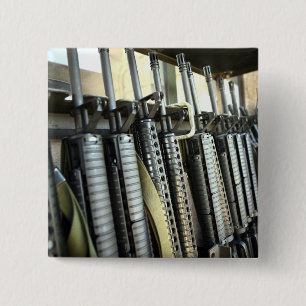 Assault rifles stand ready on the weapons rack 2 inch square button