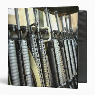 Assault rifles stand ready on the weapons rack binder