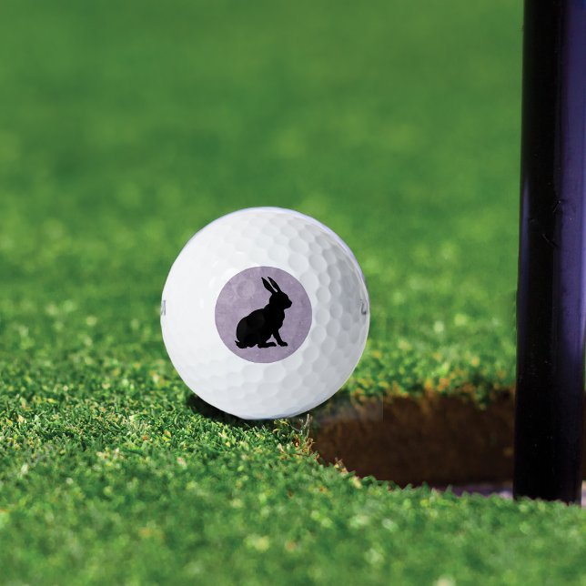 Balles De Golf Lapin noir Silhouette Lapin de Pâques (Black sitting rabbit in silhouette form on marbled light purple background on golf balls.)