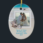 Beach Wedding Keepsake Photo Ornament<br><div class="desc">Keepsake wedding ornament with a beach theme.  Add a picture to this oval,  ceramic ornament and customize with text on both sides.   Tropical seashells decorate the frame and background image is ocean water and beach sand.  Place names,  wedding date on the front and destination location on the back.</div>