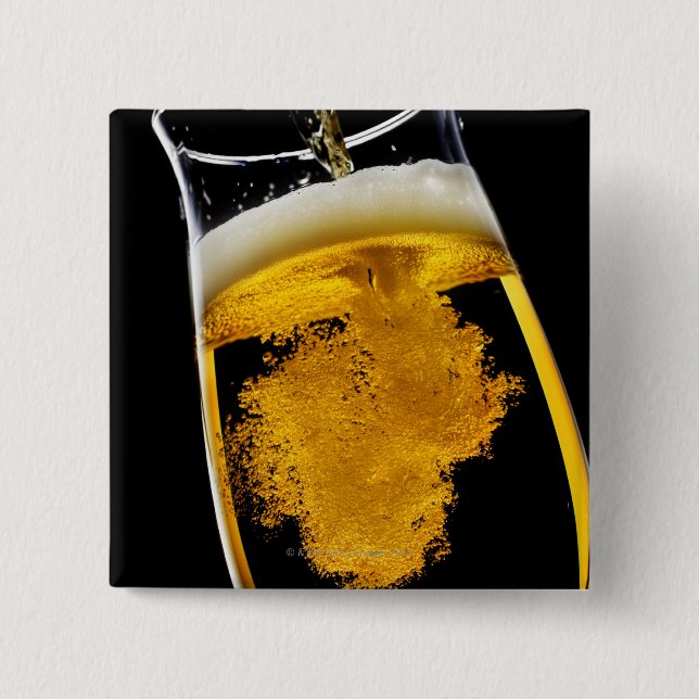 Beer been poured into glass, studio shot 2 inch square button (Front)