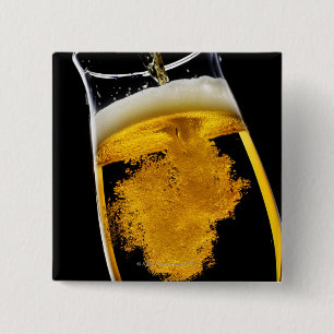 Beer been poured into glass, studio shot 2 inch square button