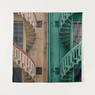 Beige and green concrete spiral stairs beside buil tapestry