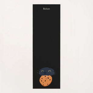 black cat holding a cookie in its teeth yoga mat