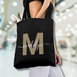 Black Gold Trendy Modern Script Name Monogram Tote Bag<br><div class="desc">Personalized Elegant Black Gold Trendy Modern Script Name Monogram Tote Bag. Add a touch of glamour and sophistication to your everyday style with this chic tote bag. Featuring a sleek gold initial (note: the gold is a flat colour, with no shimmer or foil) centred on a crisp black background, and...</div>