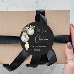 Black gold white baubles Christmas Classic Round Sticker<br><div class="desc">For a Christmas party favours or gift wrapping. An elegant,  modern black background. Decorated with white and gold baubles and some greenery and a pine cone.  Personalize and add your name,  year.  Text: Merry Christmas</div>
