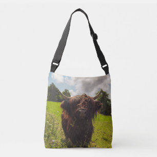 Black highland cow grazing green field sun light crossbody bag