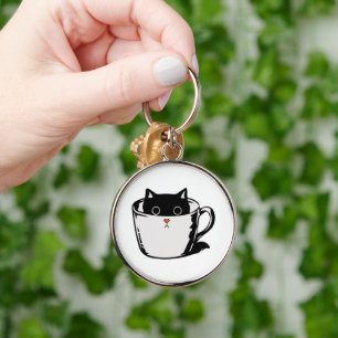 Black kitten with red nose hiding in a cup keychain