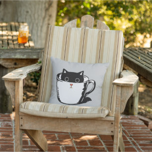 Black kitten with red nose hiding in a cup outdoor pillow