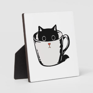 Black kitten with red nose hiding in a cup plaque