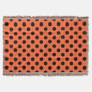 Black polka dots on orange throw blanket