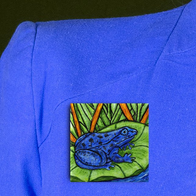 Blue Poison Frog Button (Vibrant blue frog on green lily pad in water with grass and reed plants on square pin back button.)