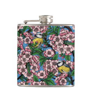 Blue tit birds in the blooming cherry tree on blue hip flask