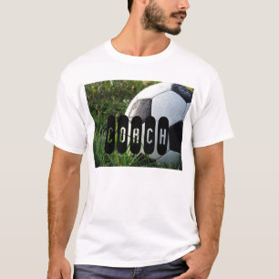 Boule de soccer noir et blanc en T-shirt en herbe
