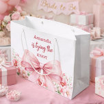 Bow She's tying the knot pink floral Bridal Shower Large Gift Bag<br><div class="desc">A white background decorated with a pink coloured bow and pink roses,  flowers. Personalize and add a name
Text: She's tying the knot.</div>