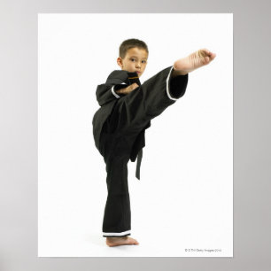 Boy (6-8) in karate outfit kicking poster
