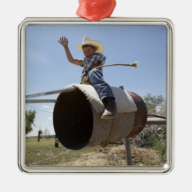 Boy (8-10) riding makeshift rodeo bull metal ornament (Front)