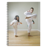 Boy and girl (4-9) practising Taekwondo kicks
