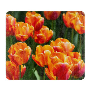 Bright orange tulips in the park cutting board