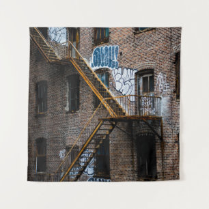 BROWN BRICK BUILDING WITH YELLOW METAL LADDER TAPESTRY