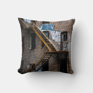BROWN BRICK BUILDING WITH YELLOW METAL LADDER THROW PILLOW