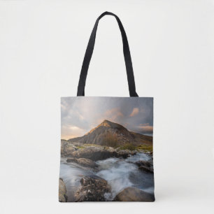 BROWN MOUNTAIN NEAR BODY OF WATER UNDER CLOUDY SKY TOTE BAG