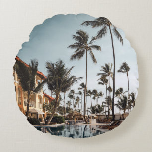 Brown wooden lounge chairs near pool surrounded by round pillow