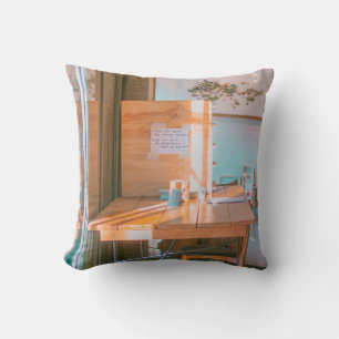 BROWN WOODEN TABLE WITH WHITE PRINTER PAPER THROW PILLOW