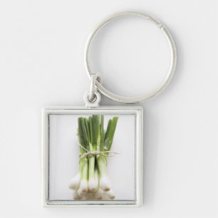 Bunch of spring onions on white chopping board keychain