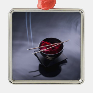 Burning incense on top of bowl of petals metal ornament