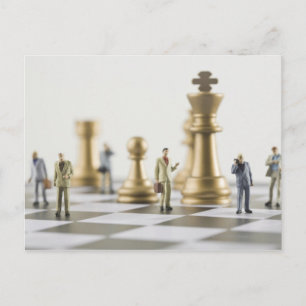 Businessmen figurines standing a top chess board postcard