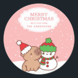 Capybara And Snowman Cute Merry Christmas Classic Round Sticker<br><div class="desc">Get into the Christmas spirit with our charming Capybara And Snowman Xmas Classic Sticker. Perfect for adding a touch of cuteness to your holiday decorations, this sticker showcases a capybara wearing a Santa hat and a snowman in a winter costume against a white and pink snow background. Personalize it with...</div>