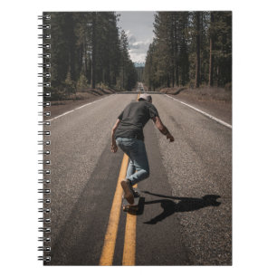 Carnet Un homme joue au skateboard sur la route le matin