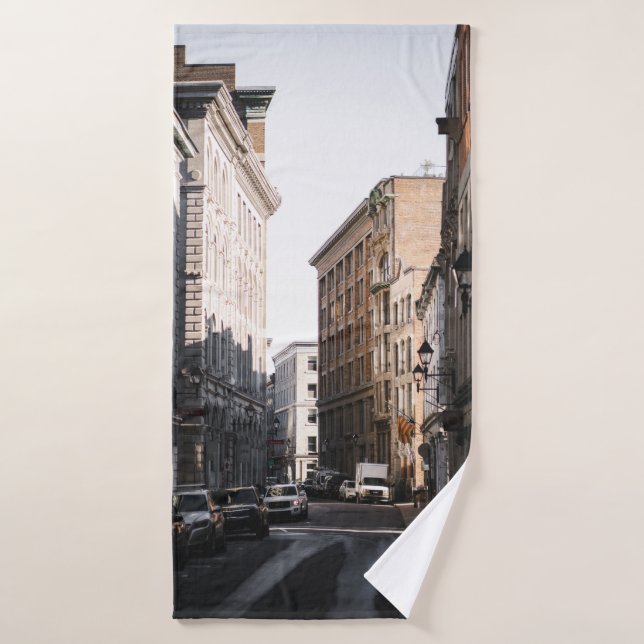 CARS PARKED ON SIDE OF THE ROAD IN BETWEEN BUILDIN BATH TOWEL (Bath Towel)