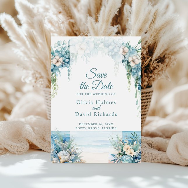 Carte de mise en vente de date de plage avec arche (Boho Blue Floral Arch Beach Save the Date Card on a sunny table in front of white pampas grass)