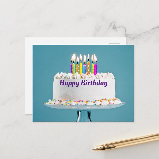 Carte de Vœux pour un Joyeux Anniversaire (A beautifully decorated birthday cake with colorful candles lit on top, set against a soft blue back)