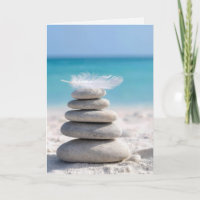 Plume blanche d'anniversaire sur un cairn de plage