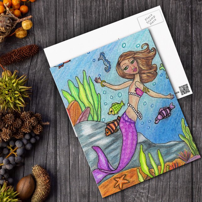 Carte postale de sirène (Pretty pink mermaid by rocks with fish in ocean on postcard.)