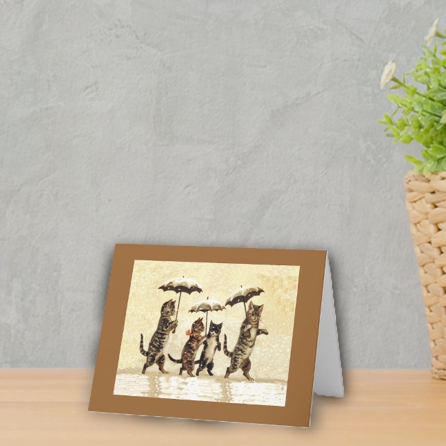 Cats in the Snow With Umbrellas Note Card (Four cats walking upright in snow with umbrellas on yellow with brown frame notecard.)