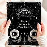 Celestial Sun Moon Stars Custom Manifestation  Planner<br><div class="desc">This captivating design features celestial elements such as the sun, moon, stars, and blooming sunflowers, all set against a bold black background. The motivational phrase "Let the Universe Be Your Guide" inspires focus and manifestation, making this design both functional and empowering. Personalized with a custom name and year, it’s perfect...</div>