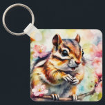 Chattering Spring Chipmunk Keychain<br><div class="desc">Talkative chipmunk sitting up on a small branch with its mouth open. Pink blossoms drift into a watercolor wash background.
Same image horizontally flipped on the back.  
AI generated.</div>