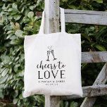 Cheers to Love Wedding Favour Tote Bag<br><div class="desc">Festive and chic wedding favour or wedding welcome tote bags feature "cheers to love" in black vintage style block and script typography with two champagne flutes joined by an effervescent heart. Personalize with your names and wedding date beneath.</div>