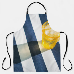 Clear drinking glass with yellow liquid apron